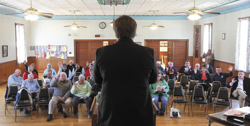 Residents vote on an article as moderator David Benier presides over the annual Benton Town Meeting inside the Benton Grange Hall recently.