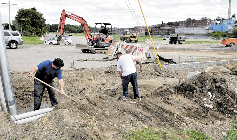 Workers bury electrical conduits beside new granite-lined walkways in the landscaping project at Head of Falls in Waterville in 2010.