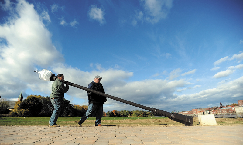 Philip Kramer, left, and Marc Leighton, both electricians with Kennebec Electric, install a light post at Head of Falls in Waterville in 2010.