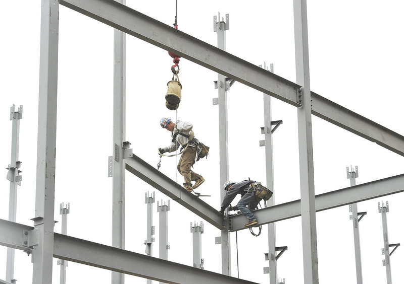 Ironworkers position steel beams at a construction site on Commercial Street in Portland. The LePage administration says the sharp drop in the number of enforcement actions by the Department of Environmental Protection’s Land Division is due to improved compliance, but critics say some development-related laws are no longer vigorously enforced.