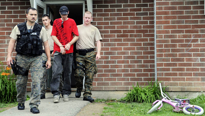 Augusta Police officers escort Matthew Jepsen, 29, of Augusta on Monday from an apartment in Augusta they raided with drug agents. Several individuals were arrested on drug charges, according to police.