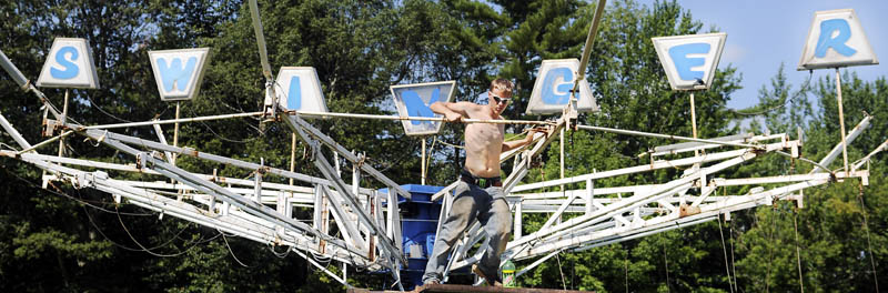 Tim Fowler rotates a ride today at the midway of the Monmouth Fair, the day before the annual agricultural exhibition opens. Gates open at 8 a.m. Wednesday and close Saturday night after the stage show. The Swinger, according to employees of midway operator Kavanaugh Amusements, is a family ride, with seats to propel people up and down while rotating in a circle at moderate speeds.