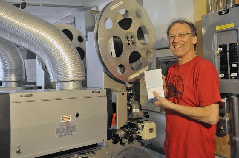 Alan Sanborn, manager at Railroad Square Cinema, holds a digital movie as he stands next to the old 35 mm projectors on Thursday.