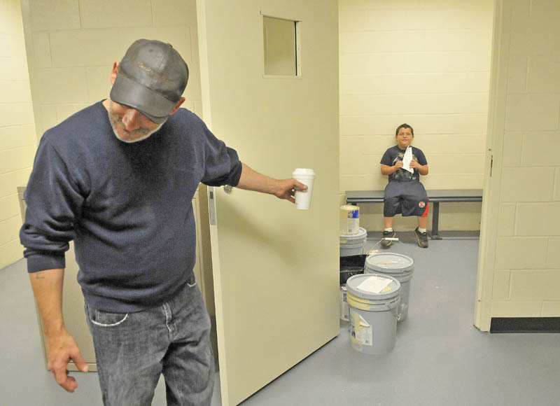 Allen Libby, 7, background, sits in one of the two holding cells in the new Waterville police station as family friend Rick Maheu, left, tries to coerce Libby's little brother James to join him during a tour of the station on Colby Circle Thursday morning.