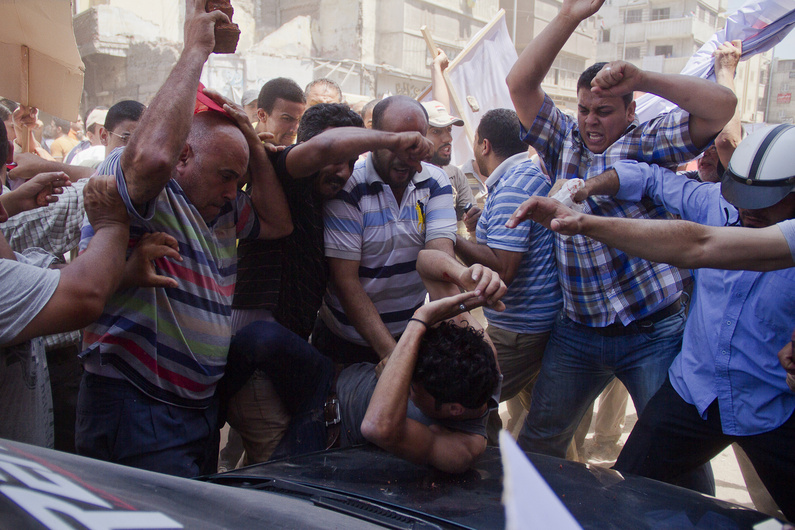 An Egyptian opposition protester is beaten by supporters of Egyptian president Mohammed Morsi, as a main raises a brick overhead, in downtown Damietta, Egypt, on Wednesday.