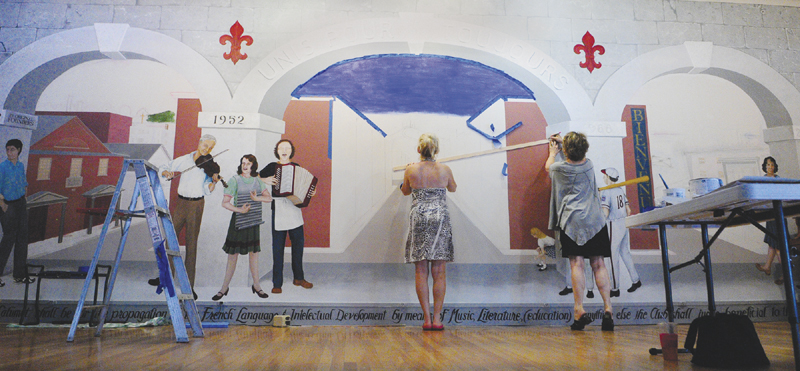 Lisa Lancaster, left, holds a straight edge while Corliss Chastain draws guide lines in pencil as they work on a mural on July 19 at Le Club Calumet in Augusta.