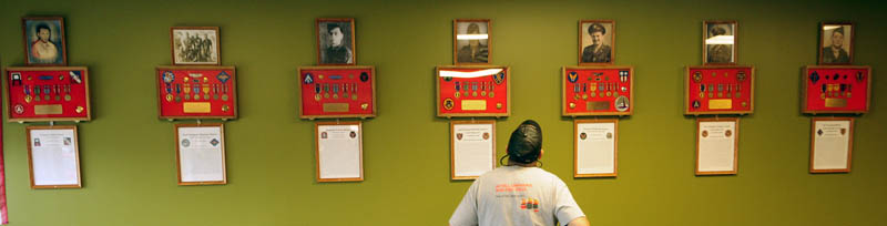 Ed Garnier, of Monmouth, looks at the memorials on the wall at TJ's Place on Route 202 in Monmouth on Tuesday. There are seven plaques, one for each of the soldiers from the town killed in action in World War II.