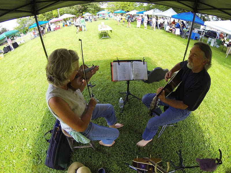Michele Roy, left, and Will West, performing as Twisted Strings, play under a tent at the Gardiner Common on Wednesday, at the Gardiner Farmers' Market. There are products from 26 vendors at the market, which is held every Wednesday, from 3 to 6 p.m.