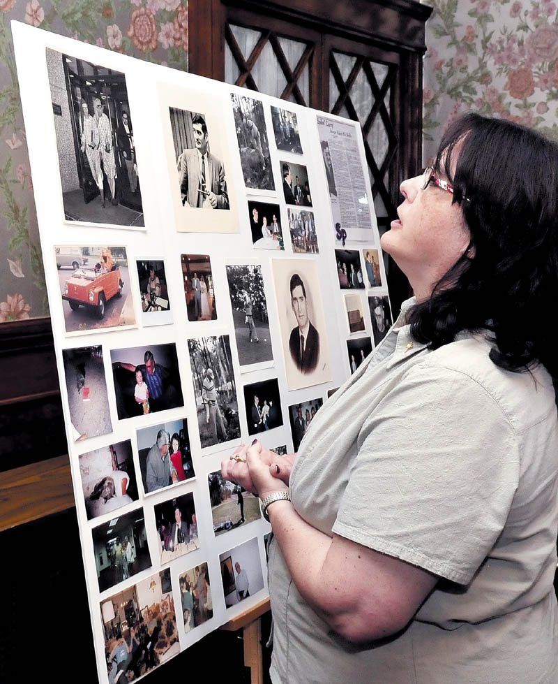 Denise Ducharme, daughter of Richard J. "Spike" Carey, looks over a photo collage of her father during a memorial service in Waterville on Monday. Carey passed away last Friday. He served many years as a legislator, mayor, town manager and director of the Maine State Lottery.