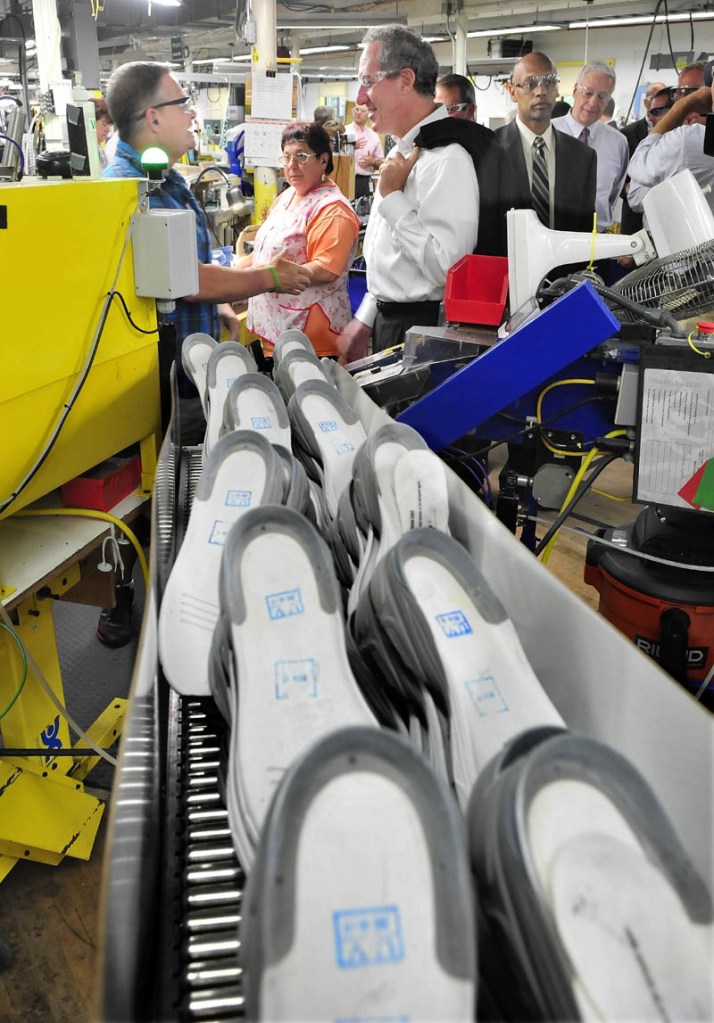 U.S. Trade Representative Michael Froman, right, speaks with New Balance employee Jim Paradis as sneakers roll on a conveyor at the Norridgewock plant today.