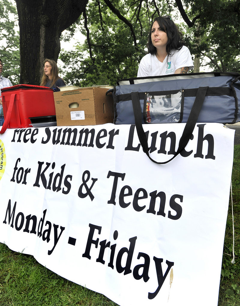 Dawn Hilton, left, and Hannah Baker staff a table serving lunches to kids last week at Deering Oaks park, a new site established this summer in Portland’s free-meal program.