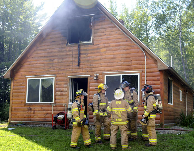 Firefighters confer today outside a residence off the Belgrade Road in Mount Vernon, after extinguishing a blaze in the home. No injuries were reported, according to Mount Vernon Fire Chief Dana Dunn.