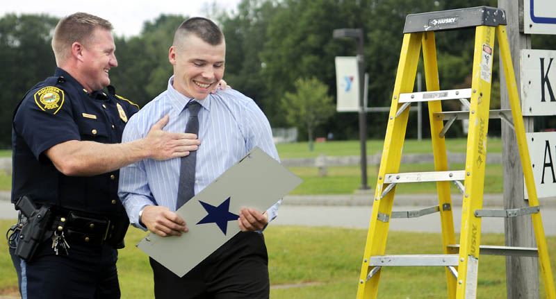 Augusta Police Officer Eric Dos Santos holds the service star that Deputy Chief Jared Mills, left, gave him after removing it from the department's sign today, at the police station in Augusta. Police and fire departments across the nation hang a blue star from their signs to honor employees who are deployed on military assignments. Dos Santos recently returned from serving a year in Afghanistan, on his second deployment with the Maine Army National Guard.