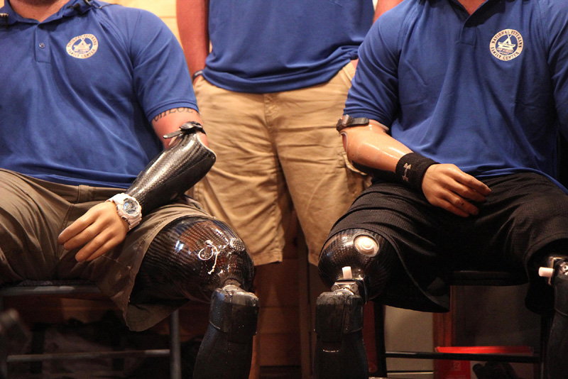 U.S. Army veteran Travis Mills, left, sits next to fellow quadruple amputee survivor Taylor Morris, right, while talking to reporters on Wednesday night in Belgrade.