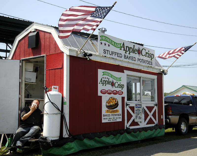 Mike Philbrick wipes his brow Tuesday while setting up his food stand at the Windsor Fair. Vendors from across Maine are arriving at the grounds of the annual agricultural exhibition that commences Sunday, August 25, and wraps up Monday, Sept. 2.
