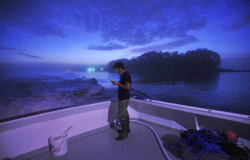 Carl Hayse, 18, texts on his cell phone as he steams to the fishing grounds on Overkill, captained by his uncle, Jim Wotton, early on July 24.