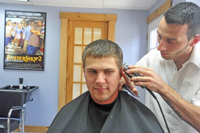 Derrik Vigue trims the hair around the ears of Josh Gilbert, 23, of Oakland, during a cut at Faded Lines Barber Shop at 99 Church St. in Oakland on Thursday.