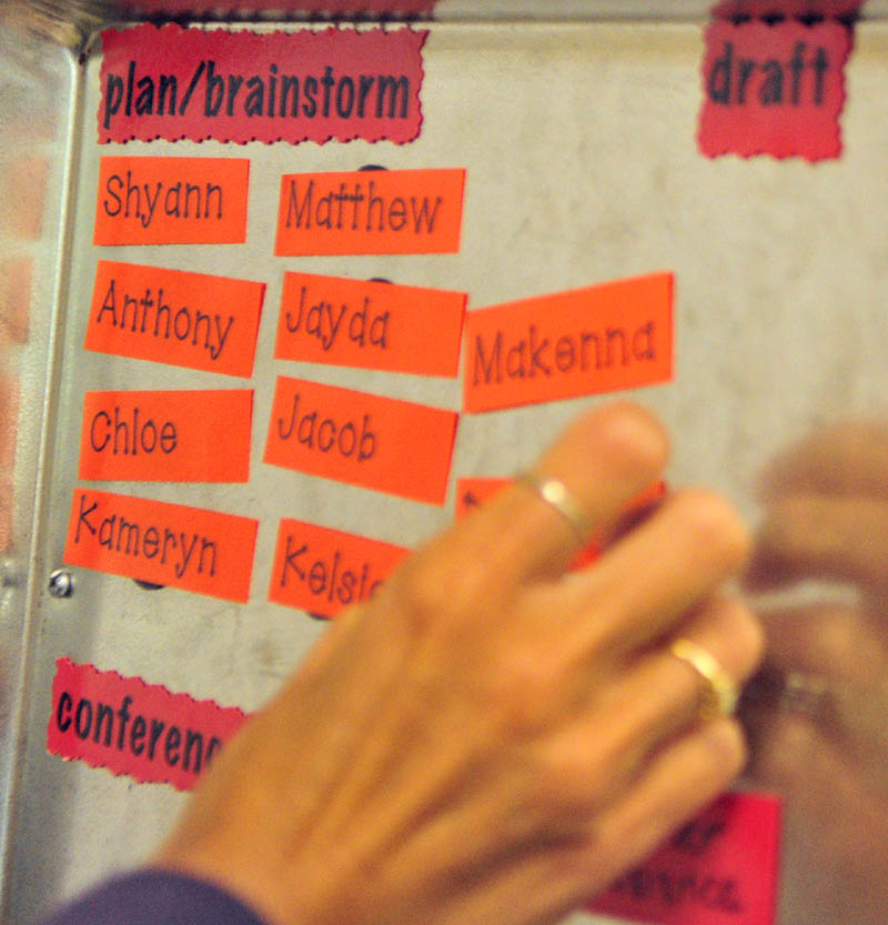 Third-grade teacher Erica Atkinson puts students' names on a magnetic writing-status board as she readies her classroom on Tuesday at Dresden Elementary School.