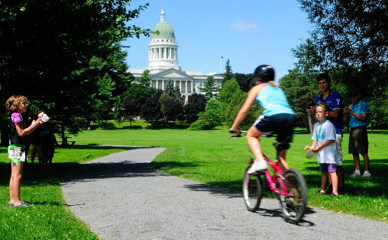 Spectators cheer for a young triathlete riding through Capitol Park during the youth division race of the Capital Y Tri today in Augusta.