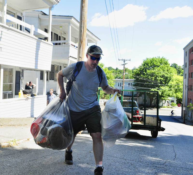 Peter Coltart carries bags of belonging towards a taxi as he moves out today at 9 Laurel St. in Augusta.