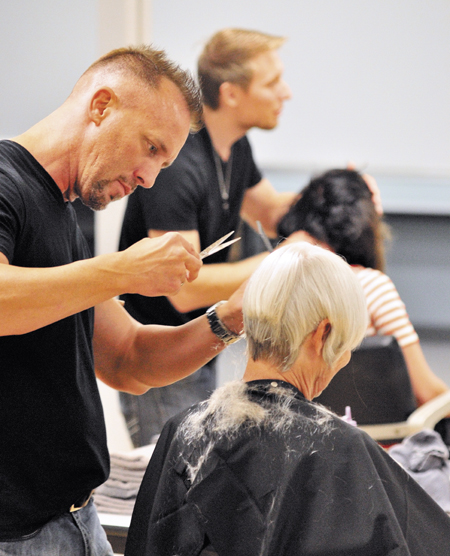 Patrick Lomantini, a hair stylist from Witchita, Kansas, cuts Marguerite Stockford's hair on Thursday at Capillo Institute in Augusta, on the first day of the third annual BarkAid 50 State Tour. Lomantini, along with Zachary DiBella, from Idaho Falls, Idaho, working in background, and Alexis Longworth, of Delaware, Ohio, not pictured, are planning to do 50 haircuts a day in each of the 50 states over their 50-day tour. It is a fundraiser for BarkAID.org, an animal charity started by Lomantini.