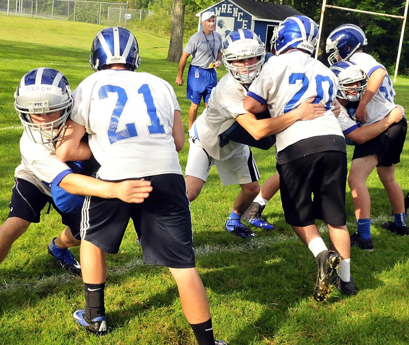 Lawrence head football coach John Hersom, back, watches as players go through drills on the first day of practice Monday morning at Lawrence High School in Fairfield. The Bulldogs, who reached the Class A state championship game last, will play in the new Class B. Maine high school football has four classes for the first time this fall.