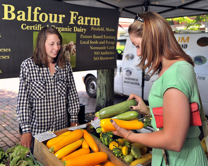 Hannah Brilliant, left, answers questions about her produce from Limington resident Michelle Twomey at the farmers market in Monument Square last month. Brilliant, who runs an organic vegetable farm in Pittsfield, says she is fielding many more questions from consumers this year about genetically modified organisms.