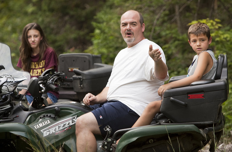 Jim Lajoie of Dayton points something out down the trail during a break while riding ATVs with his daughter Alyssa, 12, and son Ian, 8, on a trail near their home on Monday, August 26, 2013. Jim said that one of the benefits of ATV trail riding are the things you see along the way.