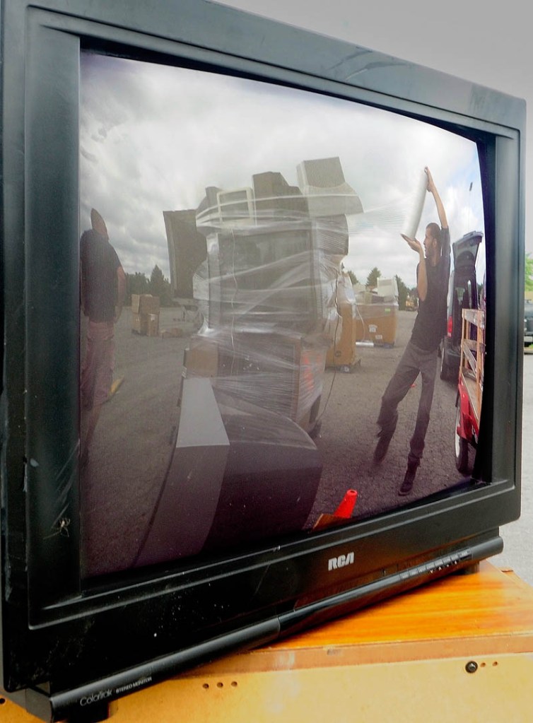 Matt McLeod, of eWaste Recycling Solutions, is reflected in the screen of an old television while wrapping up a stack of them on Saturday in the parking lot at the Augusta Civic Center. The event was a fundraiser for the United Way of Kennebec Valley's winter warming center, which opens in late December, according to executive director Rob Gordon, on Front Street near the gazebo, the same location it had last year.