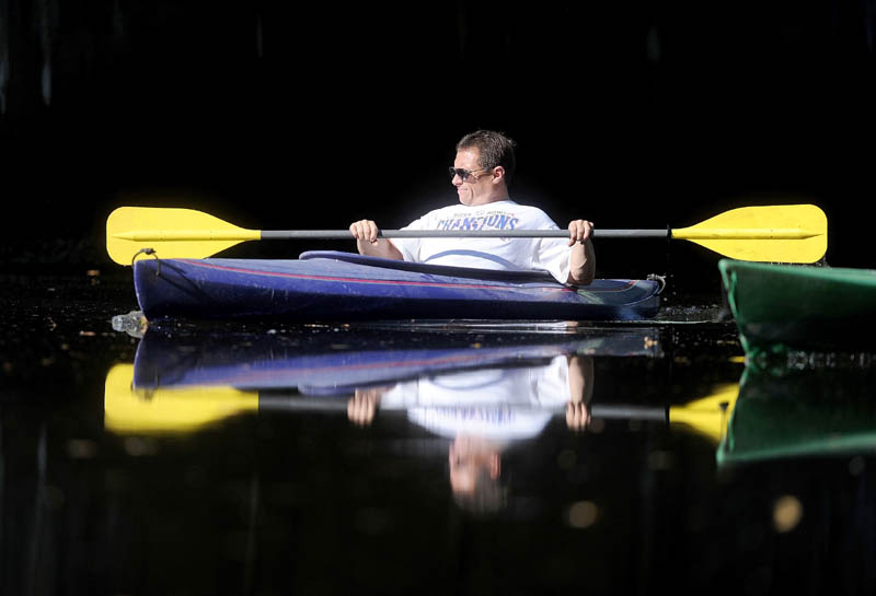 Jaimie Hart paddles his kayak through the still waters of the Messalonskee Stream near County Road in Oakland today. Sunny skies will prevail Saturday and Sunday.