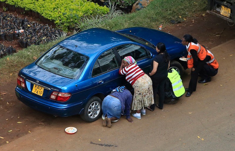 People take cover behind a car along a road during heavy gunfire at Westgate shopping centre in Nairobi September 23, 2013. A day after a Twitter post linked Maine to Saturday's terrorist attack in a mall in Nairobi, Kenya, law enforcement officials refused to say whether they are investigating the possibility that radical Islamist groups are trying to recruit new members in the state. (REUTERS/Noor Khamis) :rel:d:bm:GM1E99N1S4001