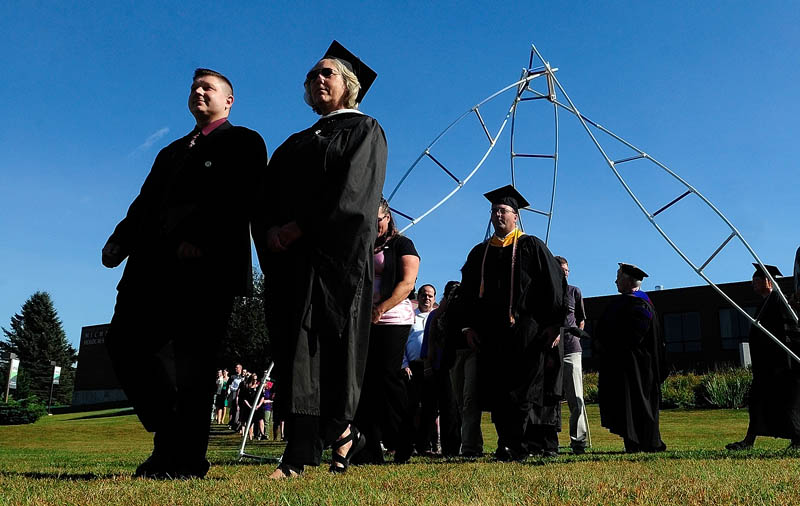 Rising Scholars and the professor that nominated them walk under a sculpture during the convocation at the University of Maine at Augusta today.