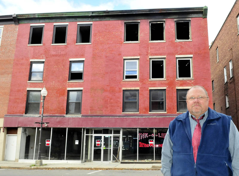 John Weeks on Wednesda stands in front of his downtown Waterville building on Main Street that was destroyed by fire in May. Weeks says he plans to raze the structure and possibly build another at the site.