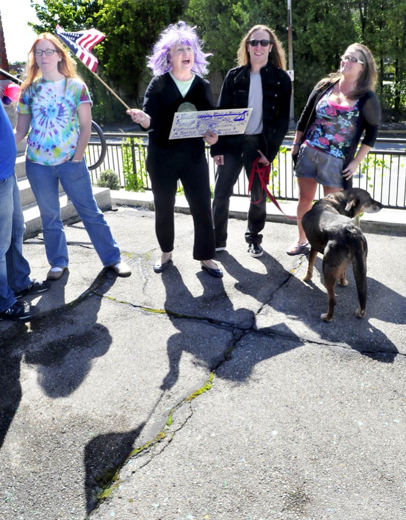As music plays on the steps of the Waterville Public Library, Katherine Dall waves an American flag as people begin to assemble ontoday for the Peace Choir on Gaia event. Sunday was the first day of an event planned to take place for the next three Sundays at noon, to promote peace and to socialize. From left are Katie Feliciano, Dall, Josh Couture and Jade Noonan.