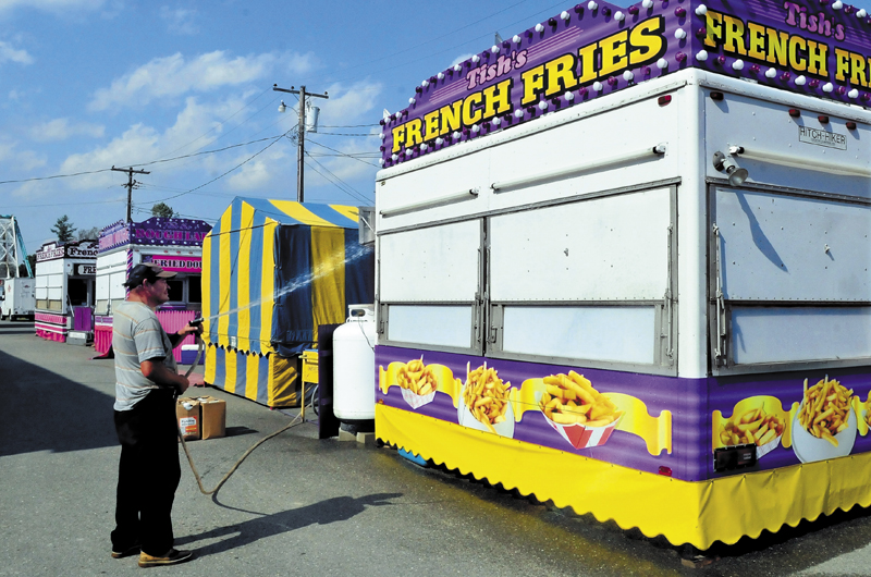 Enrique Gonzales washes down the exterior of Tish's Fries food stand at the Franklin County Fairgrounds in Farmington on Wednesday. The Farmington Fair begins this Sunday.