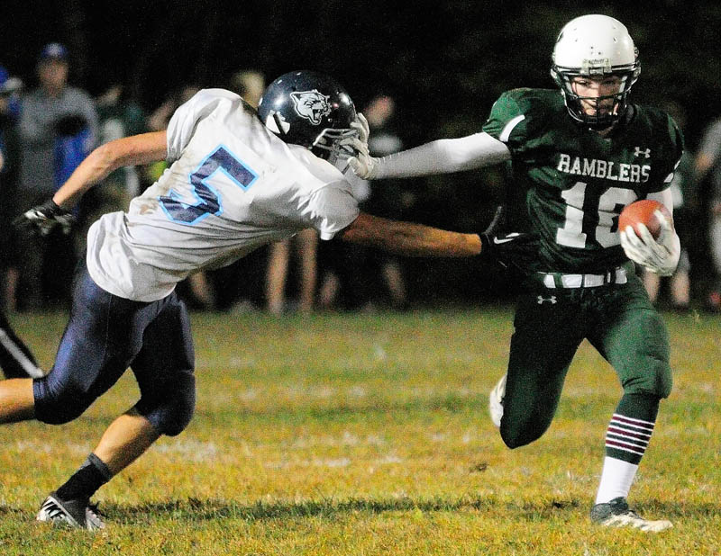 Staff photo by Joe Phelan Winthrop's Zach Glazier, center, stiff arms Dirigo's Heath Hersom during the Ramblers' 28-14 win Friday in Winthrop.