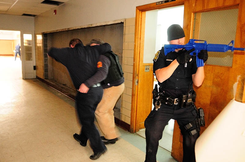 Augusta firefighter/paramedic Bill Lord, left, playing a victim, is helped down a hallway by Augusta firefighter/paramedic Randy Gordon as Augusta police officer Nico Hample provides cover, during a training exercise on Thursday at the former Hodgkins middle school in Augusta.