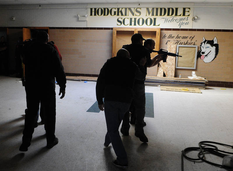 Augusta firefighter/paramedics crouch low as they follow Augusta police officers into a simulated school shooting incident Friday at the former Hodgkins middle school in Augusta.