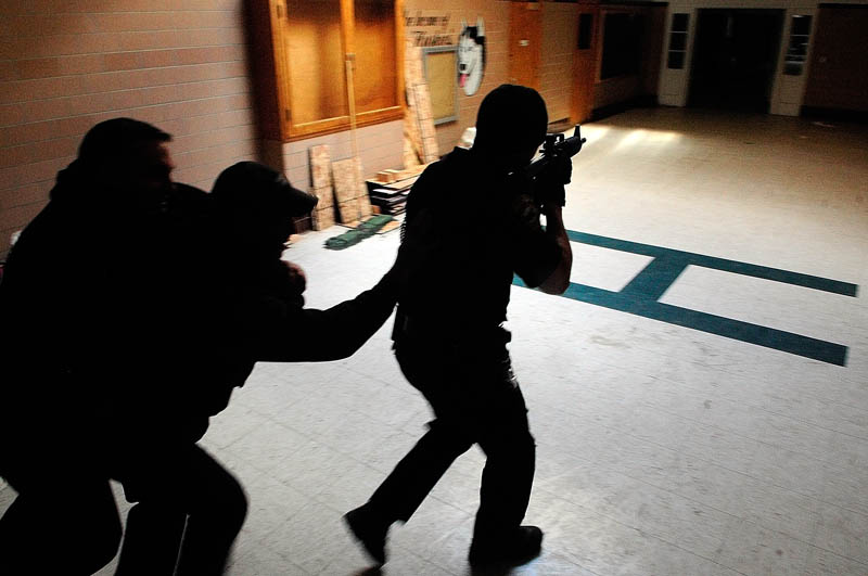 Augusta firefighter/paramedic Steve Almquist, left, playing a victim, gets carried out by firefighter/paramedic Shawn Stevens, as they follow Augusta police officer Nico Hample down a hallway during a training exercise Friday at the former Hodgkins middle school in Augusta.