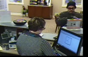 This image taken from a surveillance video shows a man robbing a teller at the Ocean Communities Federal Credit Union in Sanford on Saturday.