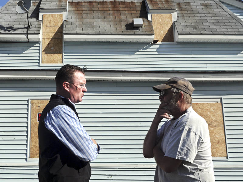 City of Augusta Code Enforcement Officer Rob Overton, left, confers with Weston MacMaster Monday outside the apartment building that MacMaster inhabited at One Jefferson Street. MacMaster was forced to relocate to an apartment in Rumford after the city ordered the Augusta apartment building closed due to safety code violations.