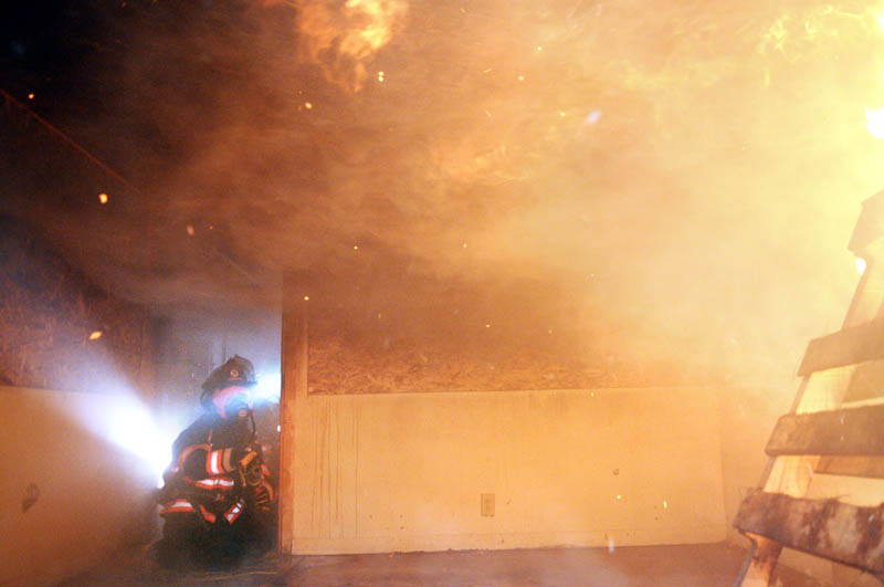 Gardiner Firefighters wait to extinguish a blaze September 23 during a controlled burn at a Gardiner home donated to the city for training. Firefighters from Gardiner and Pittston knocked down blazes ignited in rooms of the ranch house to practice putting out a fire, according to Gardiner Fire Dept. Captain Marcel DeForge.