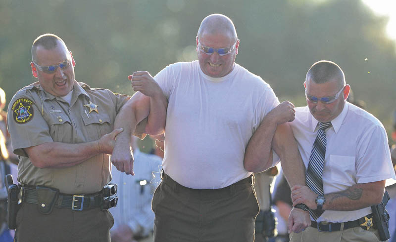 Franklin County Sheriff Scott Nichols, center, is supported by Lt. David Rackliffe, left, and Lt. David St. Laurent, right, after being shocked with a stun gun by Chief Deputy Steven Lowell during an open house Wednesday.