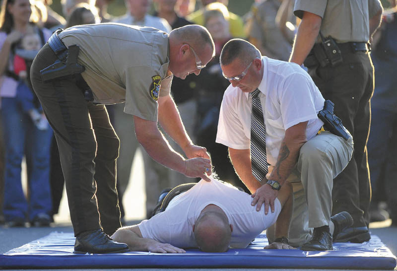 Lt. David Rackliffe, left, pulls a barb from the back of Franklin County Sheriff Scott Nichols as he is supported by Lt. David St. Laurent, right, after being shocked with a stun gun by Chief Deputy Steven Lowel during an open house on Wednesday.