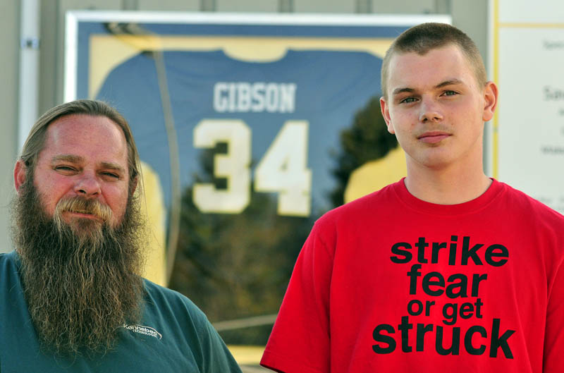 Rick and Jake Gibson stand in front of Ricky Gibson’s football jersey on Wednesday at the Ricky GIbson Field of Dreams in Readfield. The field is named after Ricky, Rick’s son and Jake’s brother. Jake is a sophomore on the Maranacook football team this fall.