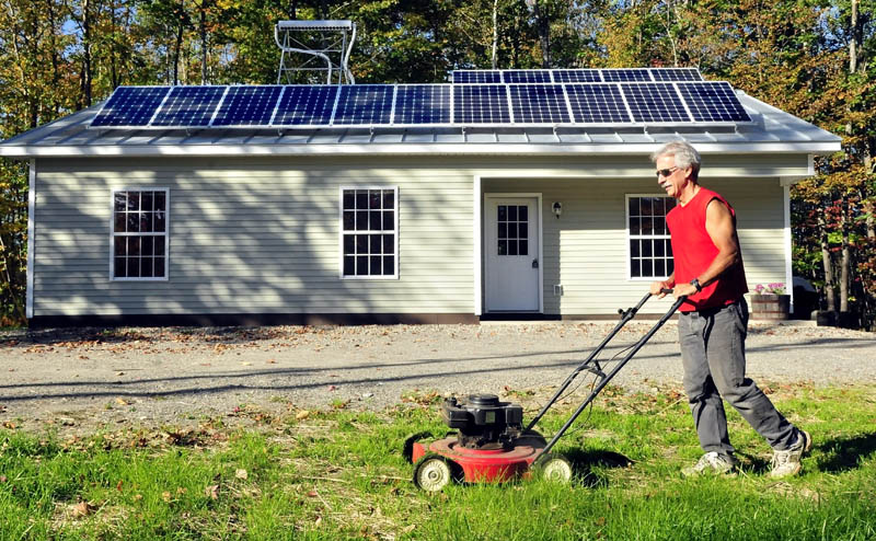 Mike Grant mows the lawn in front of the solar-powered Habitat for Humanity home recently completed on Jacques Lane in Oakland on Thursday. There will be an open house event this Sunday from 1 to 3 p.m.