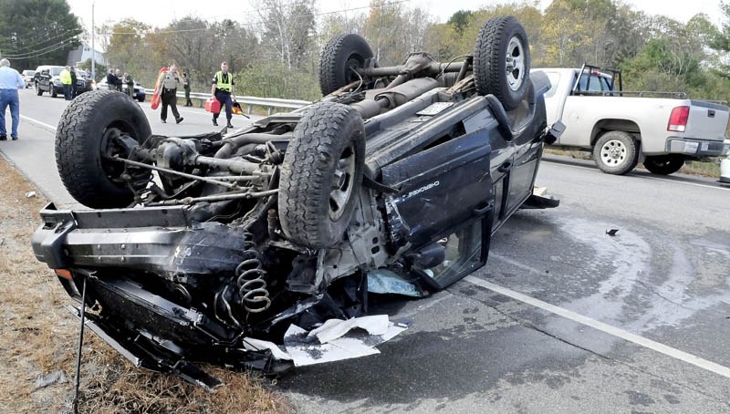 Accident re-constructionists Mike Ross of Somerset Sheriff Office, left, and Darren Foster of Maine State Police arrive to investigate a four-car accident on Route 150 in Skowhegan on Thursday. The driver of this overturned vehicle reportedly crashed into a Maine Warden Service truck that was parked on the shoulder behind a vehicle that was being investigated, causing a chain reaction.