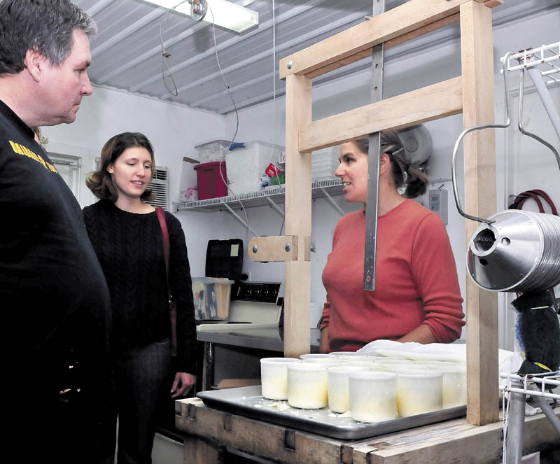 Heather Donahue, right, speaks behind a cheese press about the process of making the cheese at Balfour Farm in Pittsfield during the statewide Open Creamery Day on Sunday. Patrons, including Mike and Emily Boutin, got a chance to see how processors make various cheese products.