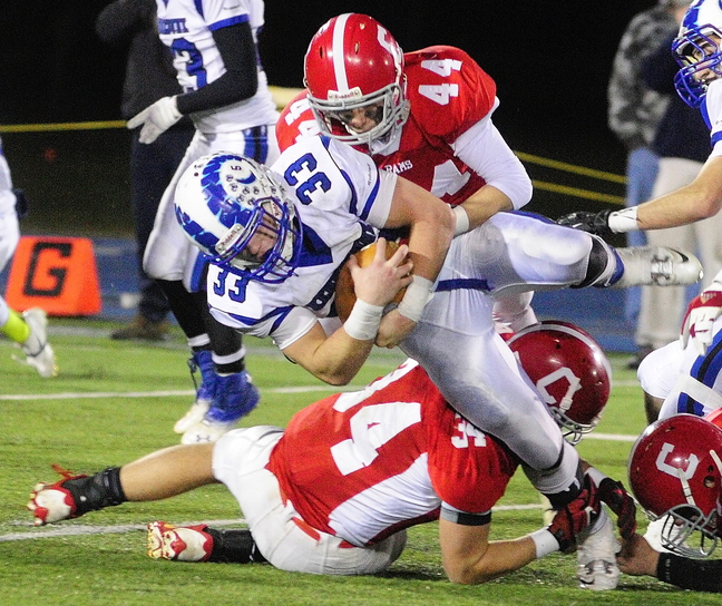 BIG TACKLE: Cony linebacker Austin Davis, top, (44) and safety Shukri Hallak, bottom, (34) bring down Kennebunk fullback Connor Donaher during the Class B state championship game on Friday in Orono.