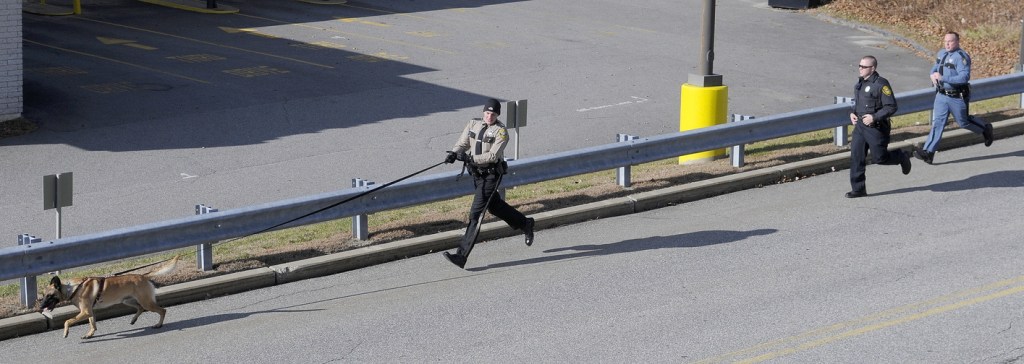 Staff photo by Andy Molloy ON TRACK: Kennebec County Deputy Aaron Moody, left, follows his dog on a track with Augusta Police Officer Christopher Hutchings, center, and State Trooper Dane Wing after the Osco pharmacy within Shaw's was robbed Monday afternoon in Augusta.